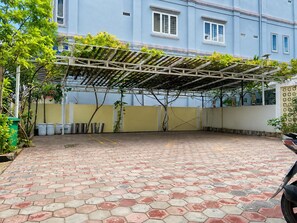 A covered outdoor area with a tiled floor, a pergola with climbing plants, and a building in the background. - AHHA Boutique Kampot (Kampot)
