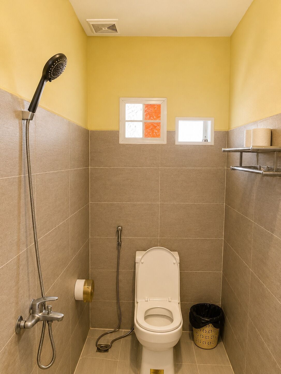 A small bathroom with a shower, toilet, and a window.