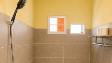 A small bathroom with a shower, toilet, and a window.