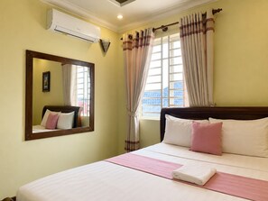 A hotel room with a bed, a large mirror, a window with curtains, and an air conditioning unit. - AHHA Boutique Kampot (Kampot)