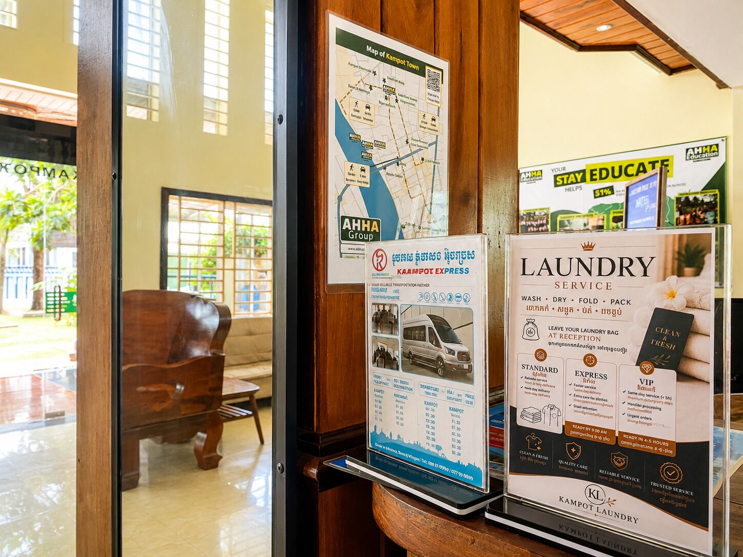 A hotel reception area with a map of Kampot Town, a KAAMPOT EXPRESS sign, and a laundry service advertisement.