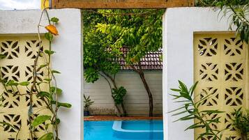 A wooden sign with 'AHHA Boutique Kayak' written on it, leading to a pool area with tiled flooring and a view of a garden.
