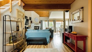 Ein gemütliches Zimmer mit einem Bett, einer hölzernen Bank, einem roten Tisch und einem Regal mit Gläsern und einer Flasche.