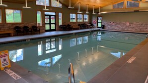 Ein Hallenbad mit deutlicher Beschilderung, einer Holzbalkendecke und Tageslicht durch Fenster.