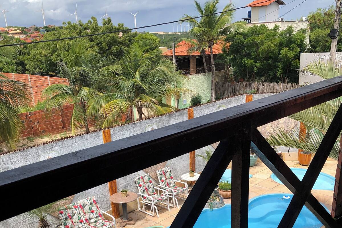 A pool area with lounge chairs and a small table, surrounded by a wooden fence.