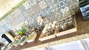 A kitchen with a tiled backsplash, a countertop with jars, and a coffee machine. - Vila do Pôr do Sol  (Aracati)