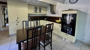 A modern kitchen with white cabinets, a black countertop, and a dining table with chairs.