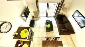 A modern living room with a dining area, a sofa, a TV, and a clock.