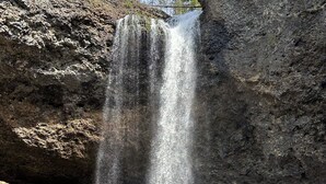 A waterfall cascading into a rocky pool surrounded by trees.