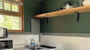 A compact kitchen with a microwave, sink, and a small refrigerator.