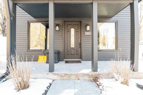 A gray house with a dark front door, two windows, and a covered porch. - Magical Home Located in Windham and Catskills (Windham)