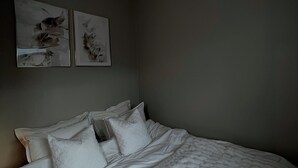A bedroom with a bed, white bedding, two wall-mounted artworks, and a ceiling fan. - Heart of Trondheim (Trøndelag)