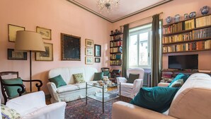 A living room with a white sofa, armchairs, a coffee table, a bookshelf, and a television. - Elegante e Raffinato in Zona Crocetta by Wonderful Italy (Turin)