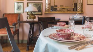A dining table set with pink and white floral tableware, surrounded by chairs. - Elegante e Raffinato in Zona Crocetta by Wonderful Italy (Turin)