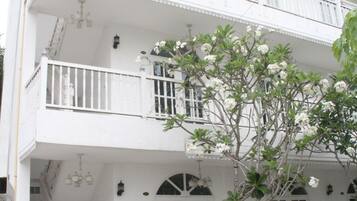 A two-story building with white exterior walls, a balcony on the upper floor, and a staircase leading to the entrance.