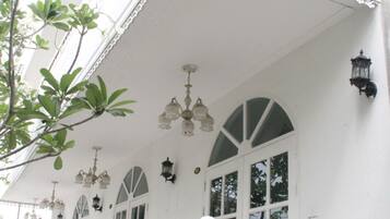 A white building with a balcony, multiple windows, and hanging light fixtures.