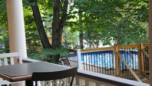 A wooden deck with a white railing overlooking a swimming pool. - Auberge Comme au premier jour (Saint-Pacôme)