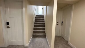 A carpeted staircase in a hallway with white walls and doors. - Private Cozy 1 Bedroom Basement Suite (Winnipeg)