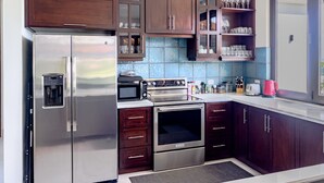 A modern kitchen with stainless steel appliances, dark wood cabinets, and a tiled backsplash. - Luxury Home With Ocean View (Provincia de Guanacaste)