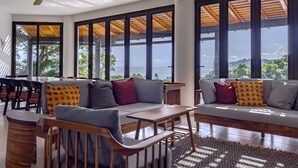 A spacious living area with a view of the ocean, a wooden ceiling fan, and a dining area with a table and chairs. - Luxury Home With Ocean View (Provincia de Guanacaste)