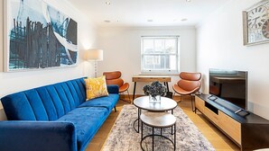 A modern living room with a blue sofa, a round coffee table, and a TV stand.
