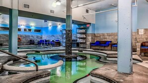 A spa area with multiple hot tubs, seating areas, and a central column. - Exquisite condo, Mountain Views (Canmore)