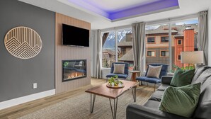 A modern living room with a fireplace, comfortable seating, and a view of mountains. - Exquisite condo, Mountain Views (Canmore)