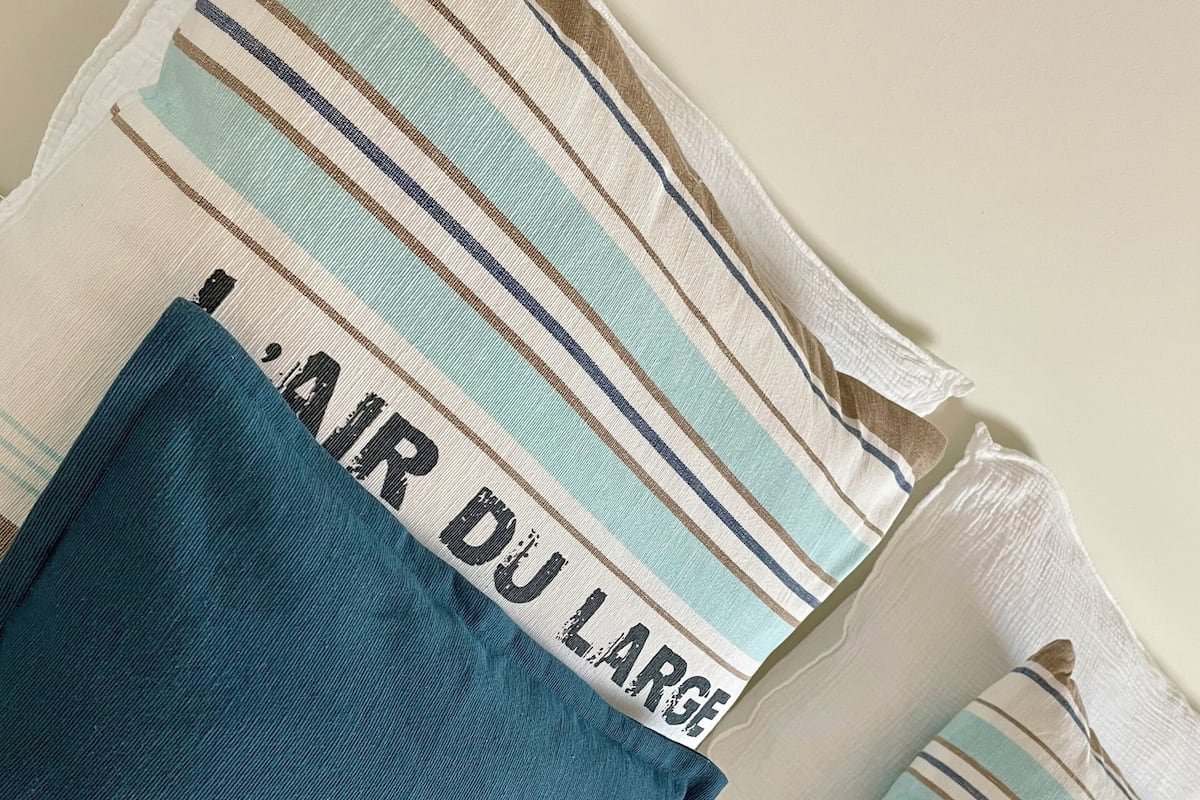 A bed with striped bedding and a blue pillow.