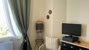 Ein Schlafzimmer mit einem Bett, einem Fernseher auf einer Kommode, einem Sessel und einer Lampe.