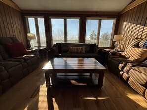 A cozy living room with a wooden floor, a central coffee table, and two sofas with cushions.