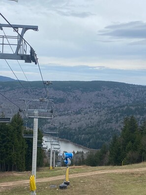 A ski lift with chairs and cables, a mountain view, and a forested landscape.