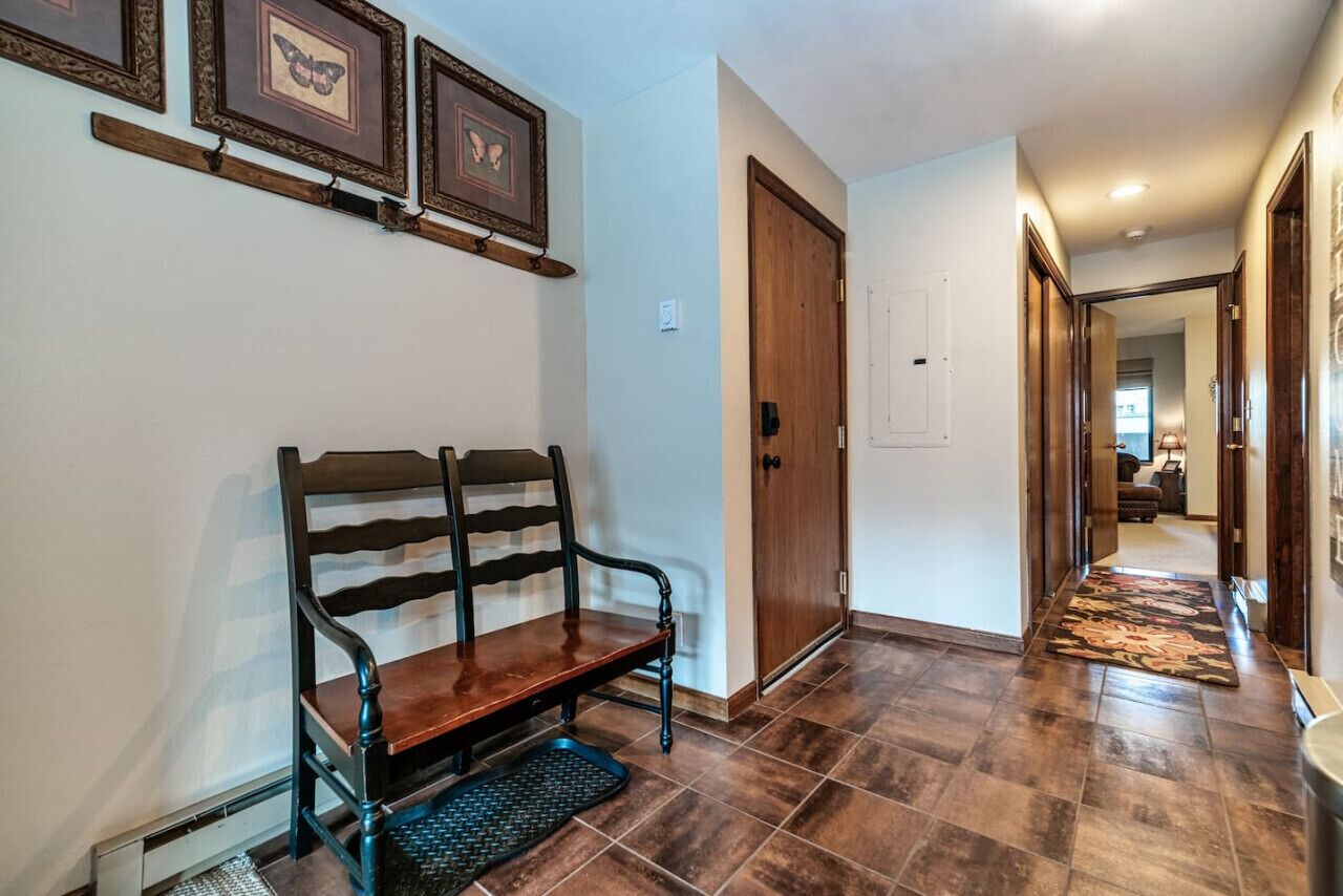 A hallway with a wooden bench, a door, and a patterned rug.