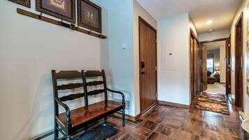 A hallway with a wooden bench, a door, and a patterned rug.