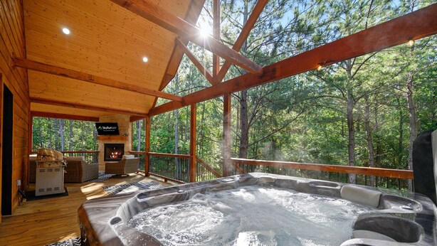 Une terrasse en bois avec un jacuzzi, des sièges d’extérieur et une cheminée.