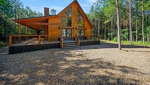 Une cabane dotée d’un grand porche à l’avant, d’une façade en bois et d’une allée gravillonnée.