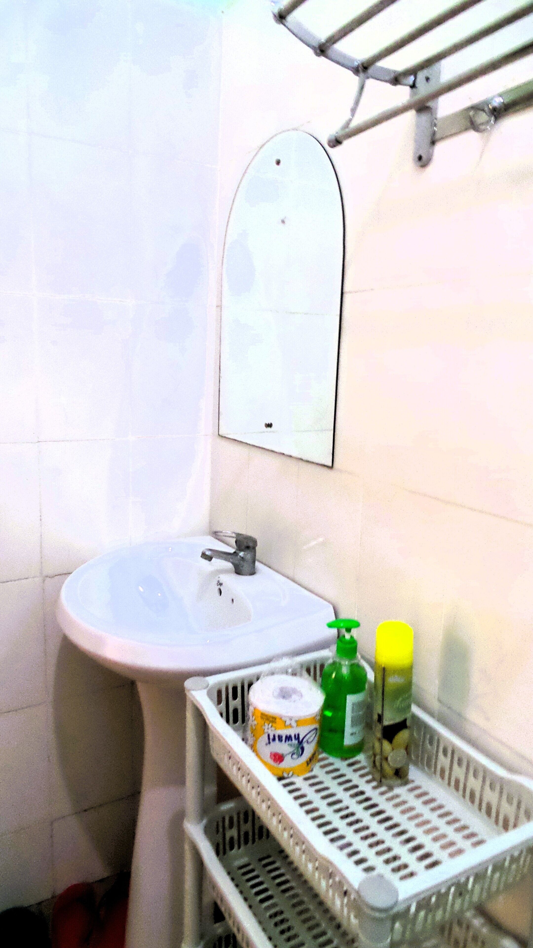 Une salle de bain équipée d’un lavabo, d’un miroir et d’une étagère où sont rangés les articles de toilette.