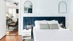 A bedroom with a large bed, two bedside tables, a ceiling fan, and a mirror on the wall. - Gorgeous Apt in Heart of Downtown: The Hall House (Wilmington)