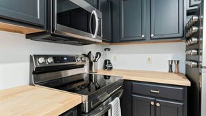 A modern kitchen with black cabinets, stainless steel appliances, and wooden countertops. - Gorgeous Apt in Heart of Downtown: The Hall House (Wilmington)