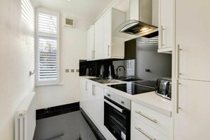 Een koelkast, een oven, een waterkoker, eettafels