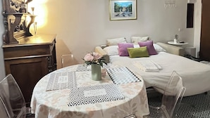 Un dormitorio con cama, mesita de noche, lámpara y un cuadro en la pared.