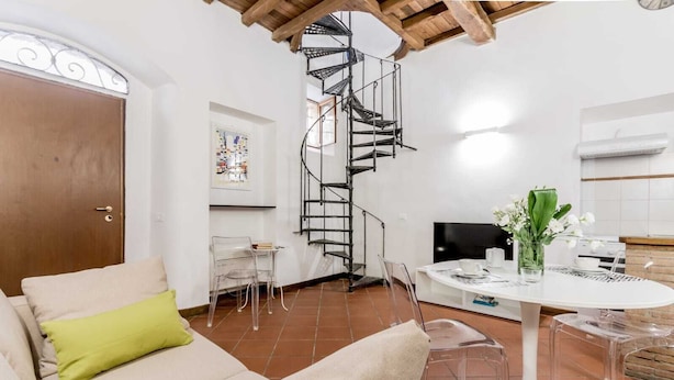 Una sala de estar moderna con una escalera en espiral, un comedor y una cocina.