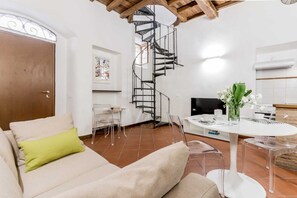 A modern living room with a spiral staircase, a dining area, and a kitchen.