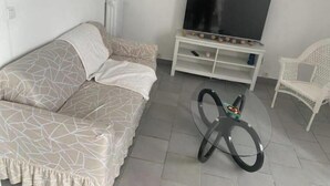 A living room with a sofa, a glass coffee table, a TV on a stand, and a white chair. - T3 Marseille 10mn drive from Velodrome & beach (Marseille)
