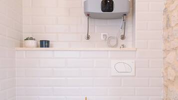 Un baño con inodoro blanco, bidé y calentador de agua instalado en la pared.