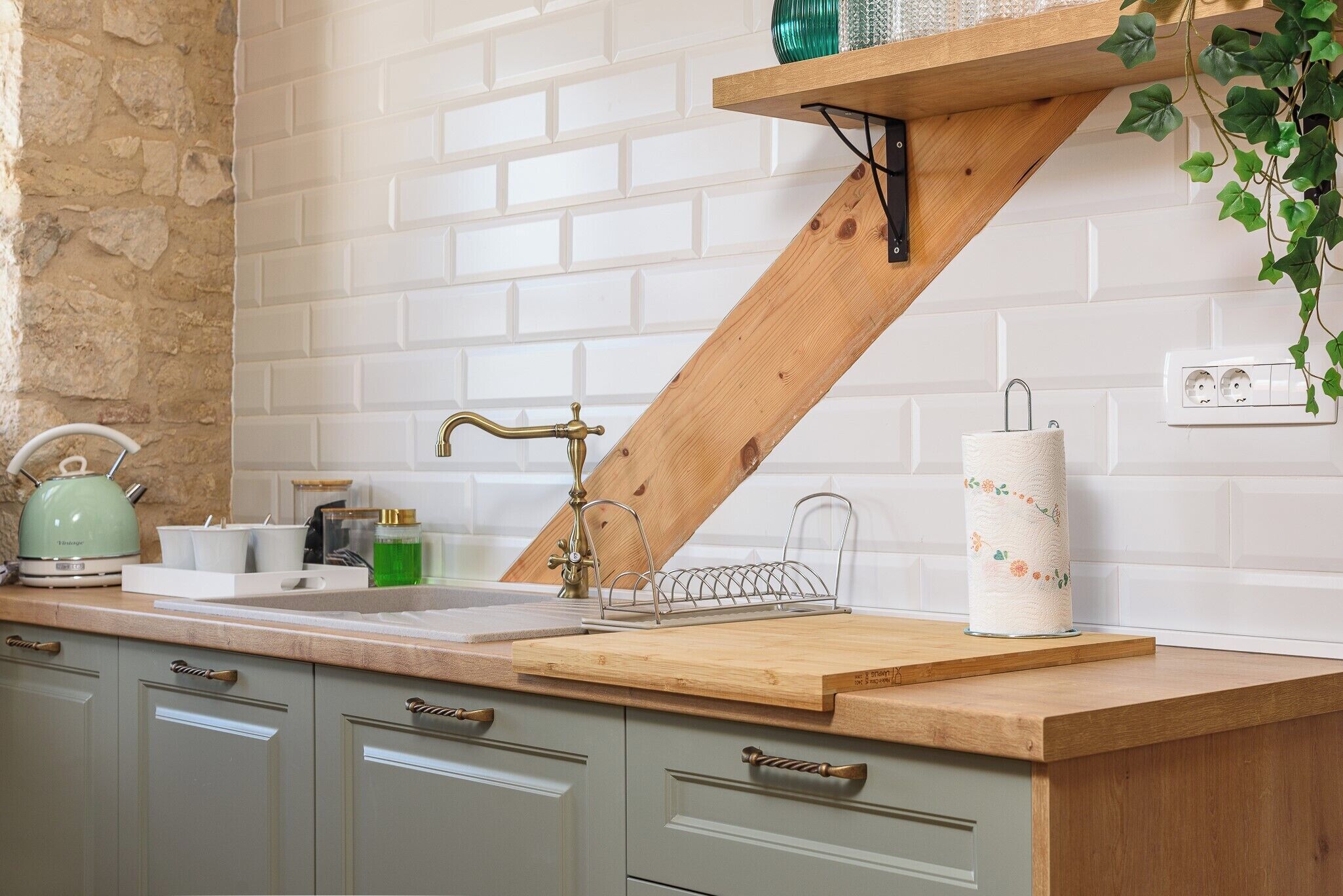 A kitchen with a wooden countertop, a sink, and a hanging plant.