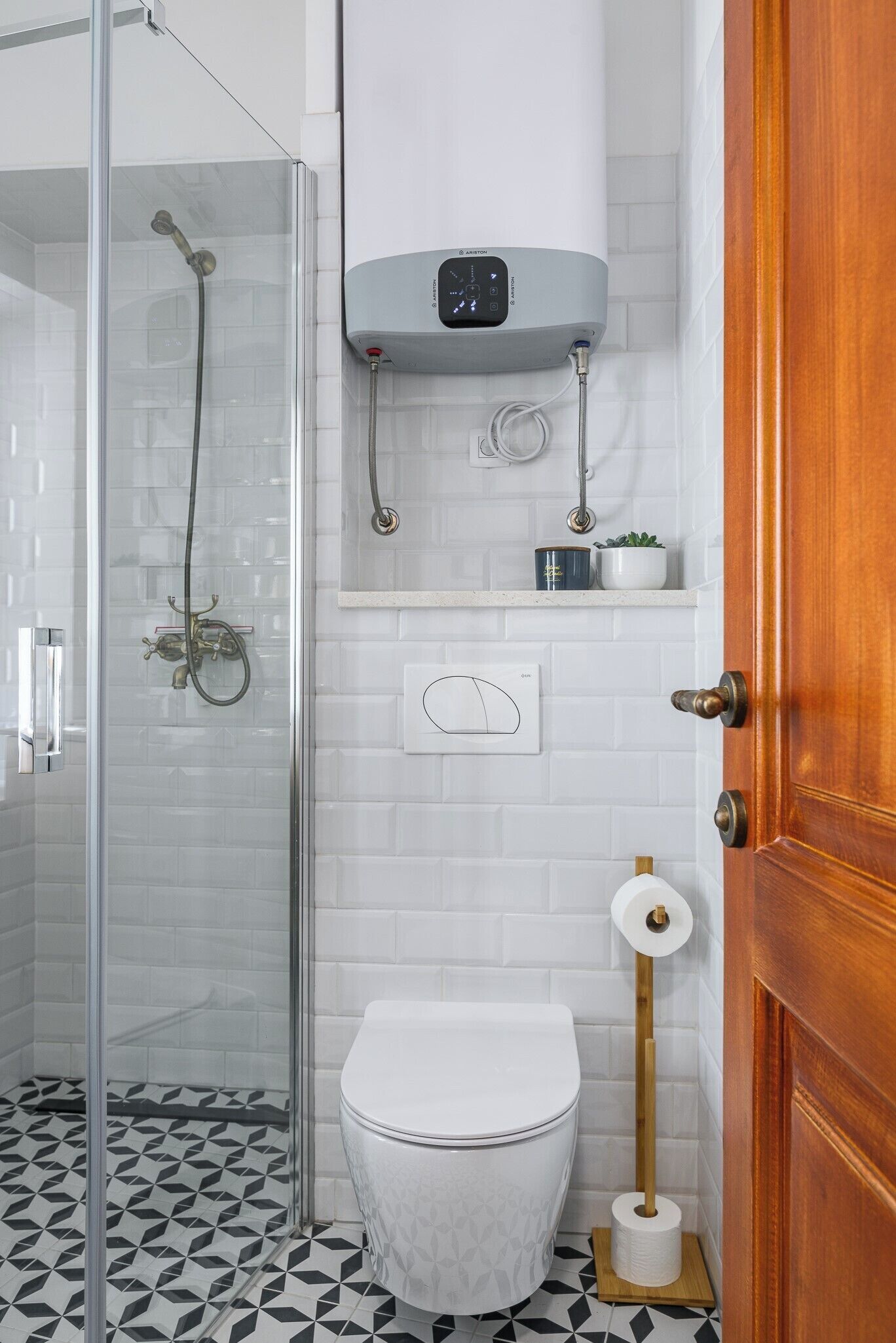 Un baño con cabina de ducha de vidrio, inodoro, calentador de agua y dispensador de papel higiénico.