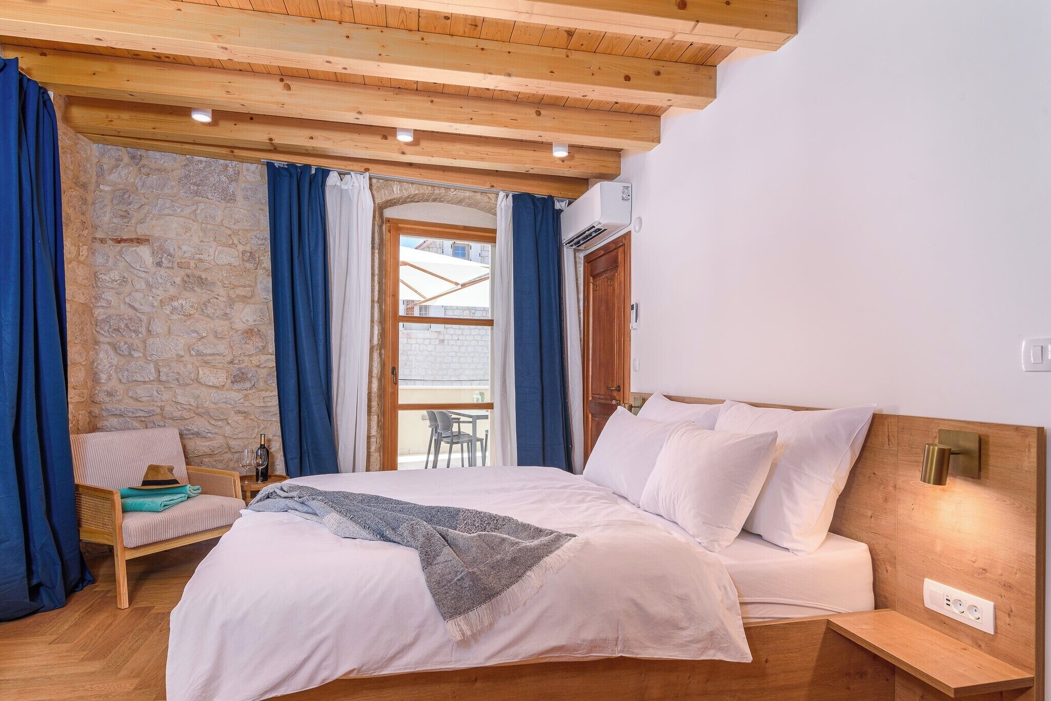 Una camera da letto con un letto, una sedia, un tavolo e un muro in pietra.