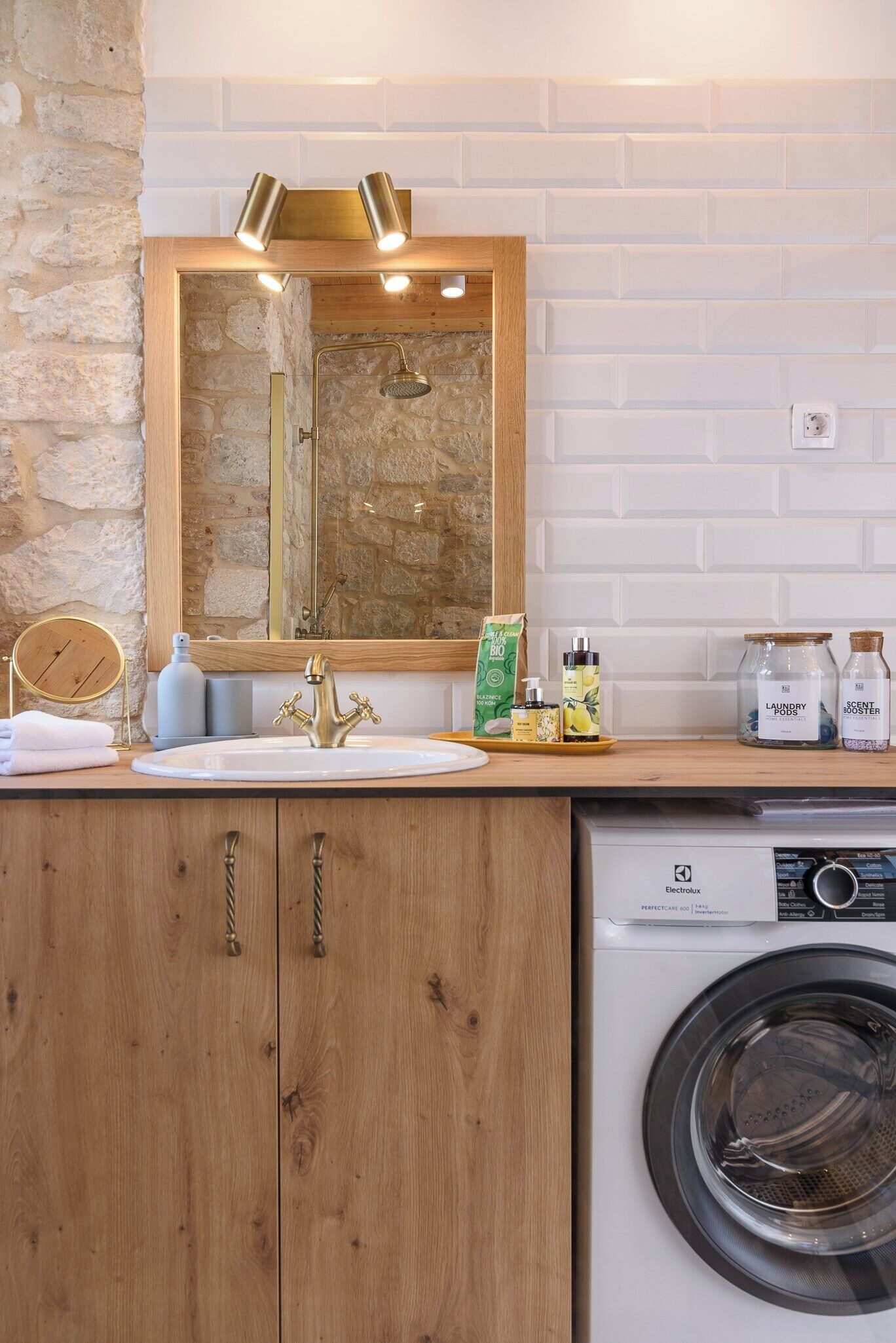 Un baño con tocador de madera, lavamanos, espejo, ducha y lavadora.