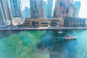 Una zona moderna frente al agua, con edificios altos, un puerto deportivo con barcos y una plaza central con zonas verdes.