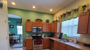 A kitchen with wooden cabinets, a stainless steel oven, and a tiled floor. - Spacious 5-Bdrm 4 bth pool home w/game room close to Theme Parks Spring Break (Kissimmee)
